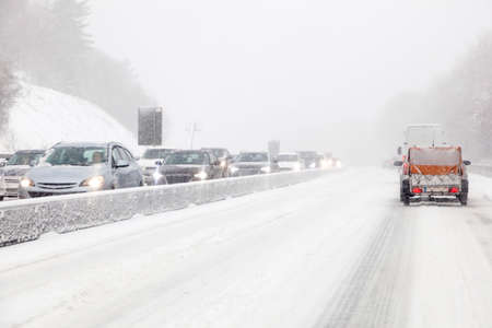 Cars driving on a highway covered with snow during a snowstorm in winterの写真素材
