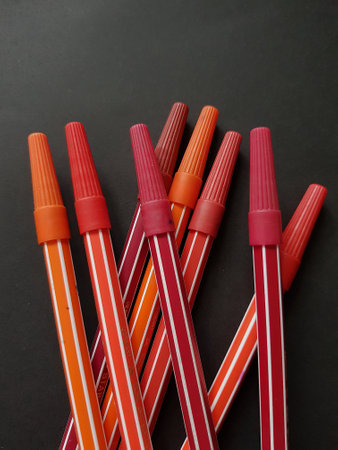 Colored markers on a black background, close-up, top view