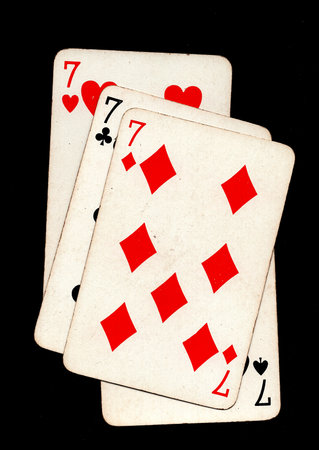 A hand of four vintage playing cards of the same value isolated on a black background.の写真素材