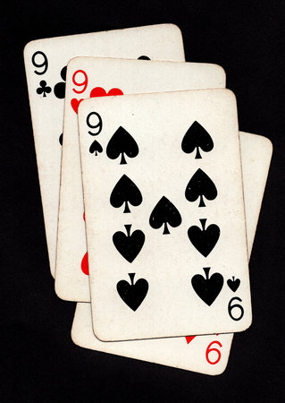 A hand of four vintage playing cards of the same value isolated on a black background.の写真素材