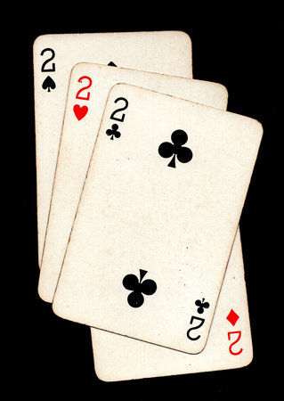 A hand of four vintage playing cards of the same value isolated on a black background.