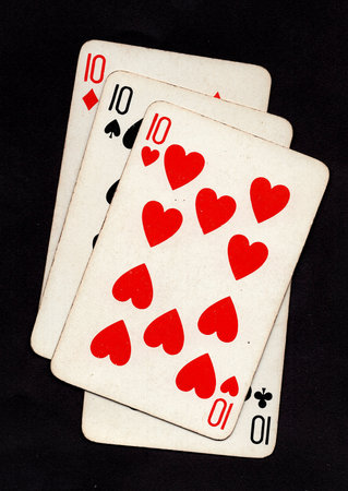A hand of four vintage playing cards of the same value isolated on a black background.の写真素材