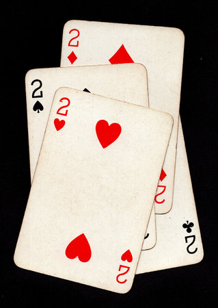 A hand of four vintage playing cards of the same value isolated on a black background.の写真素材