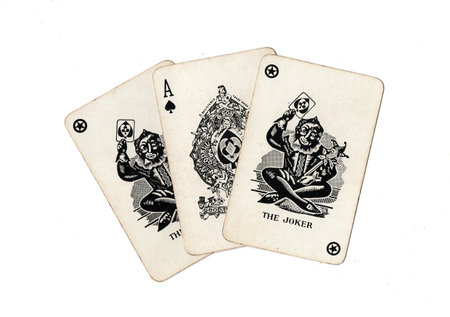 A hand of vintage playing cards showing a pair of jokers and one other card isolated on a black...