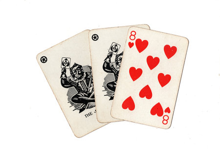 A hand of vintage playing cards showing a pair of jokers and one other card isolated on a black...
