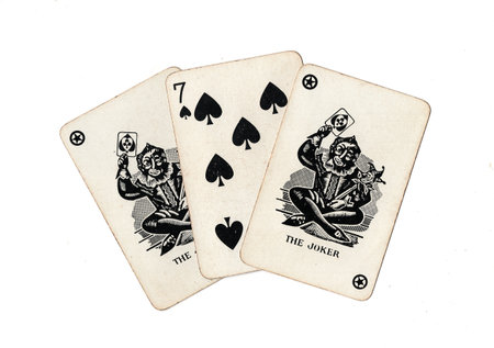 A hand of vintage playing cards showing a pair of jokers and one other card isolated on a black...