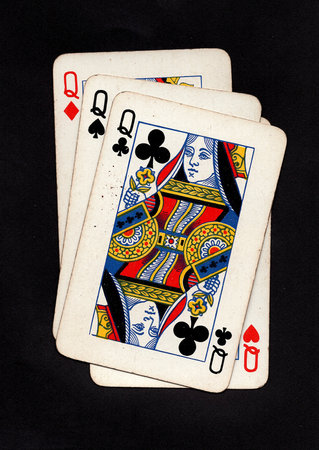 Four vintage playing cards showing queens isolated on a black background.