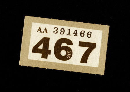 A vintage raffle ticket in sepia on a black background.の写真素材