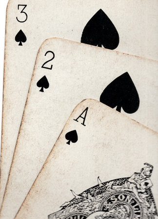Close up detail showing a run of three vintage playing cards in the same suit.