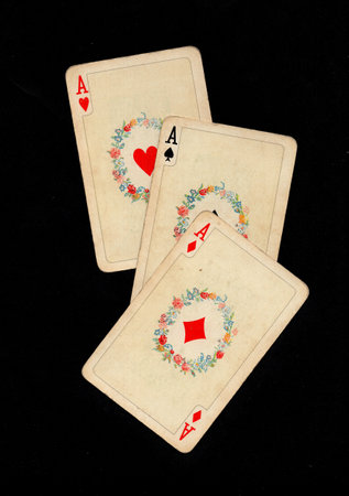 A hand of three vintage picture playing cards isolated on a black background.の写真素材