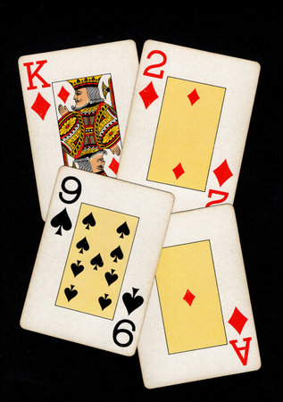A hand of vintage playing cards isolated on a black background.の写真素材