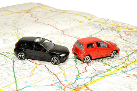 Two small red and black toy cars on a paper road map 