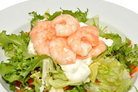 A plate of fresh salad leaves and pink peeled prawns in a white bowl の写真素材
