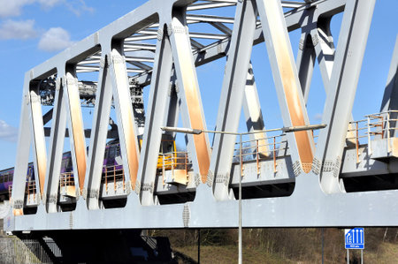A commuter train passing over a Warren truss steel girder bridge in Brinnington, Stockport, Greater...