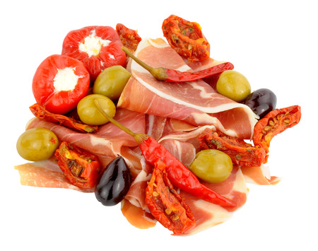 Thinly sliced Spanish Serrano ham with olives and peppers isolated on a white background