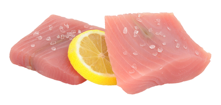 Two fresh raw uncooked yellow fin tuna steaks with lemon slice isolated on a white backgroundの写真素材