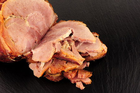 Roasted ham bacon meat joint on a stone slate backgroundの写真素材