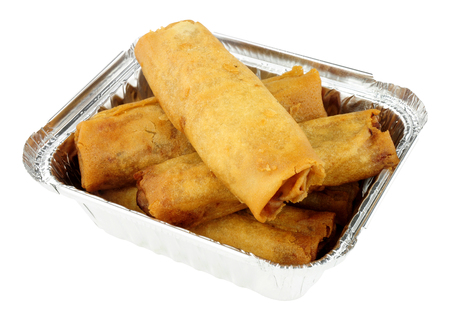 Chinese crispy vegetable filled spring rolls in an aluminium foil take away tray isolated on a white...