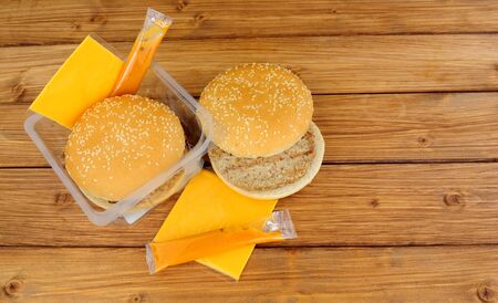 Two microwave beefburgers with cheese and sauce on a wooden backgroundの写真素材