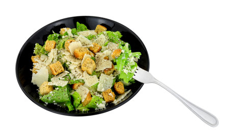Classic Caesar salad with romaine lettuce and parmesen cheese shavings served in a black dish isolated on a white backgroundの写真素材