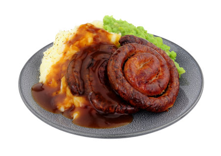 Cumberland pork sausage swirl and mashed potato meal with mushy peas and gravy isolated on a white backgroundの写真素材
