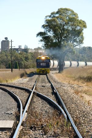 A train travelling on a single line between an industrial complex and the main line