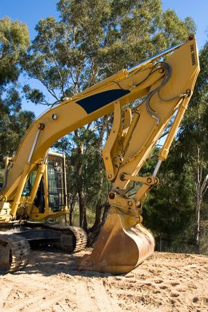 An excavator parked beside a country road.