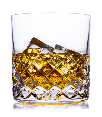 A crystal glass containing scotch whisky and ice, shot on white with a small reflectionの写真素材
