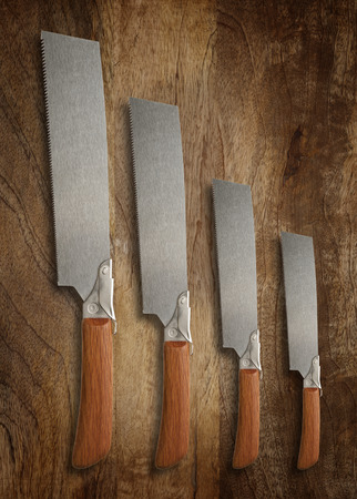 A selection of precision carpentry hand saws on a wooden backdrop, with room for textの写真素材