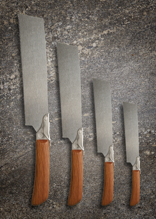 A selection of precision carpentry hand saws on a stone backdrop, with room for textの写真素材