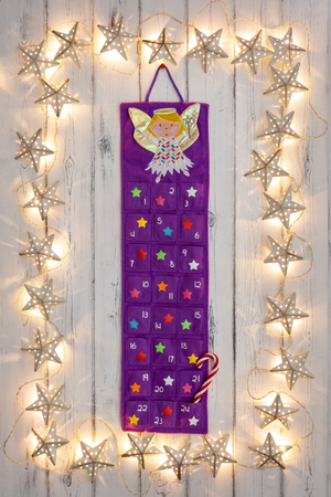 A border of golden star christmas lights, with a advent calander and candy stick in the middle, on a destressed woodern backgroundの写真素材