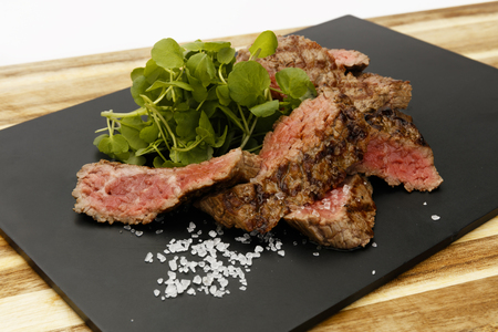 Succulent and juicy rare beef steak, with watercress garnish, on a slate plateの写真素材
