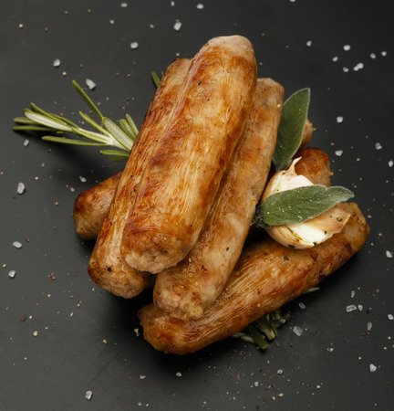 Grilled seasoned tastey sausages with a garlic and herb garnish, on a slate plateの写真素材