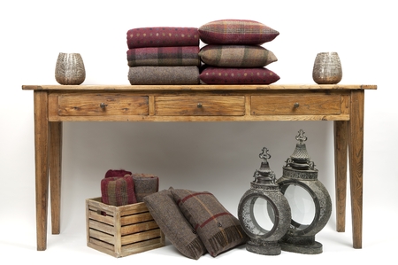 Sideboard style wooden table with cushions and throws on a white backgroundの写真素材