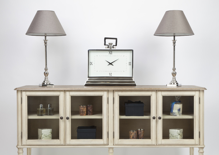 Glass fronted sideboard and ornaments with lamps and a large clock on a white backgroundの写真素材