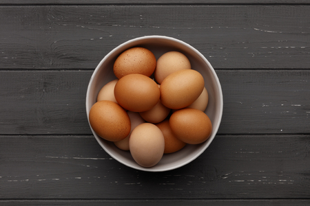 A bowl of fresh eggs on a distressed wooden background, shot from aboveの写真素材