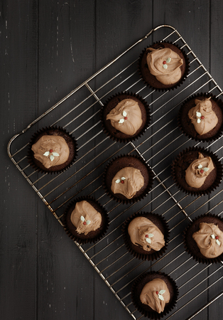 Fairy cakes on a cooling tray on a distressed grey wooden background, shot from aboveの写真素材