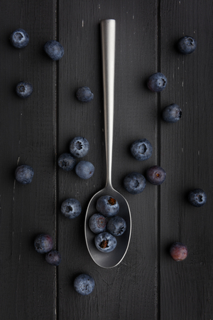 blueberries and silver spoon on dark grey wooden backgroundの写真素材