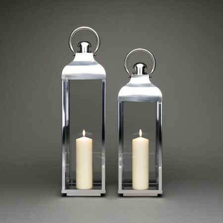 Two large candle holding lanterns, with lit candles on a dark grey background.の写真素材