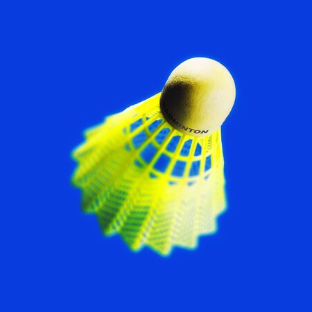 Abstract view of abright yellow badminton shuttlecock on a blue background, with a shallow depth of fieldの写真素材