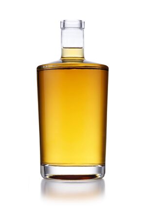 A full angular shaped bottle of golden whisky, with no label or branding, isolated on white with a slight reflectionの写真素材