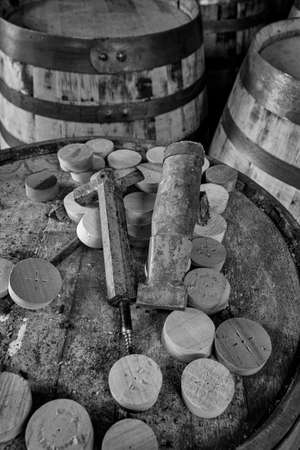 Tools to insert and remove bungs from whisky barrels, on the top  of a dusty old whisky barrel, black and white imageの写真素材