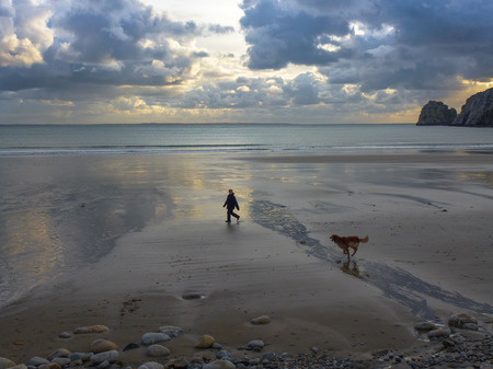 A woman and her dog walking on La Palue beach, Brittanyの写真素材