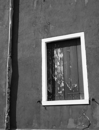 shuttered windows on an old wall with white frame