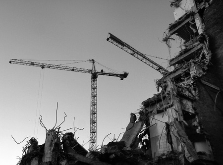 Demolition site with cranes rubble and partially demolished concrete buildingの写真素材