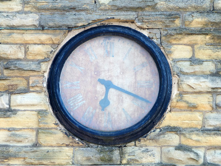 old rusty faded clock on a brick wall