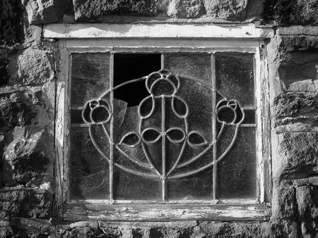 broken old decorative lead glass window in a white wooden frame in a abandoned building