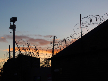 barbed wire and security camera with evening sky and sunsetの写真素材