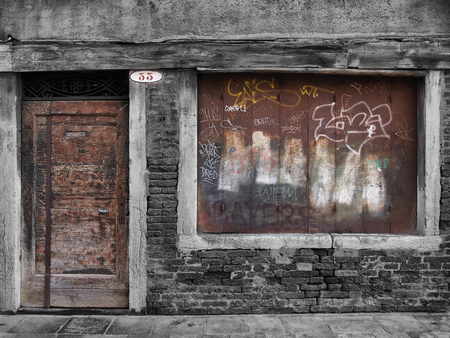 derelict decaying shop building with boarded up window and vandalismの写真素材