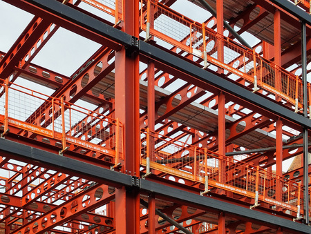 metal framework of new building development with a network of orange steel girders  and safety fencingの写真素材